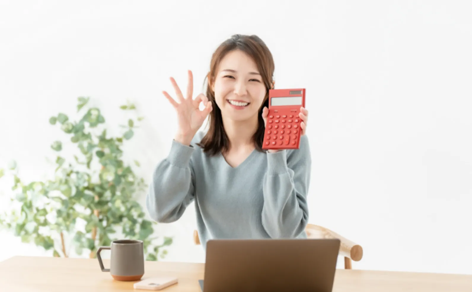 電卓を手に持ち節約をする女性の写真