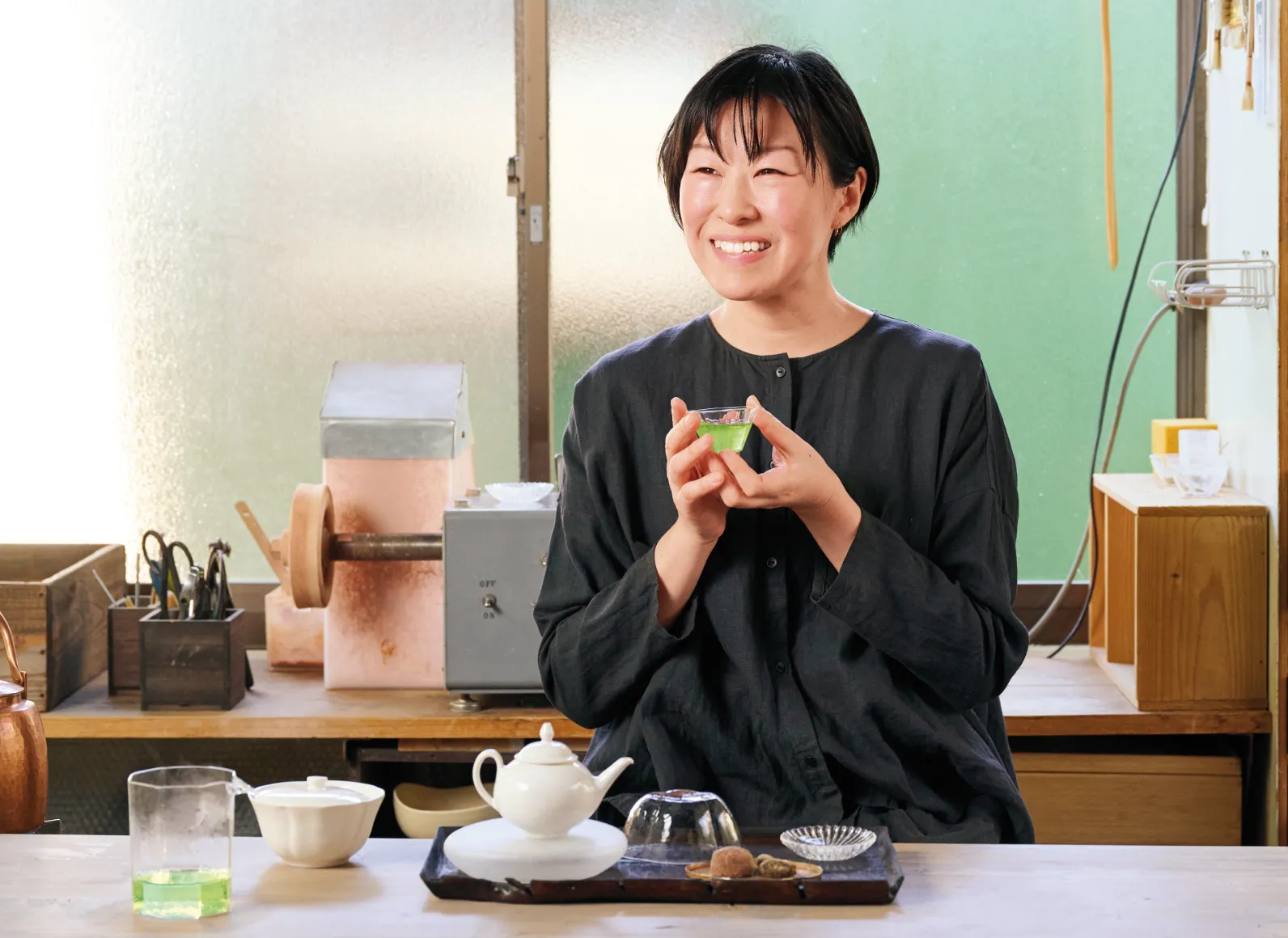 ガラスの器に入ったお茶を持つ小林希さんの画像