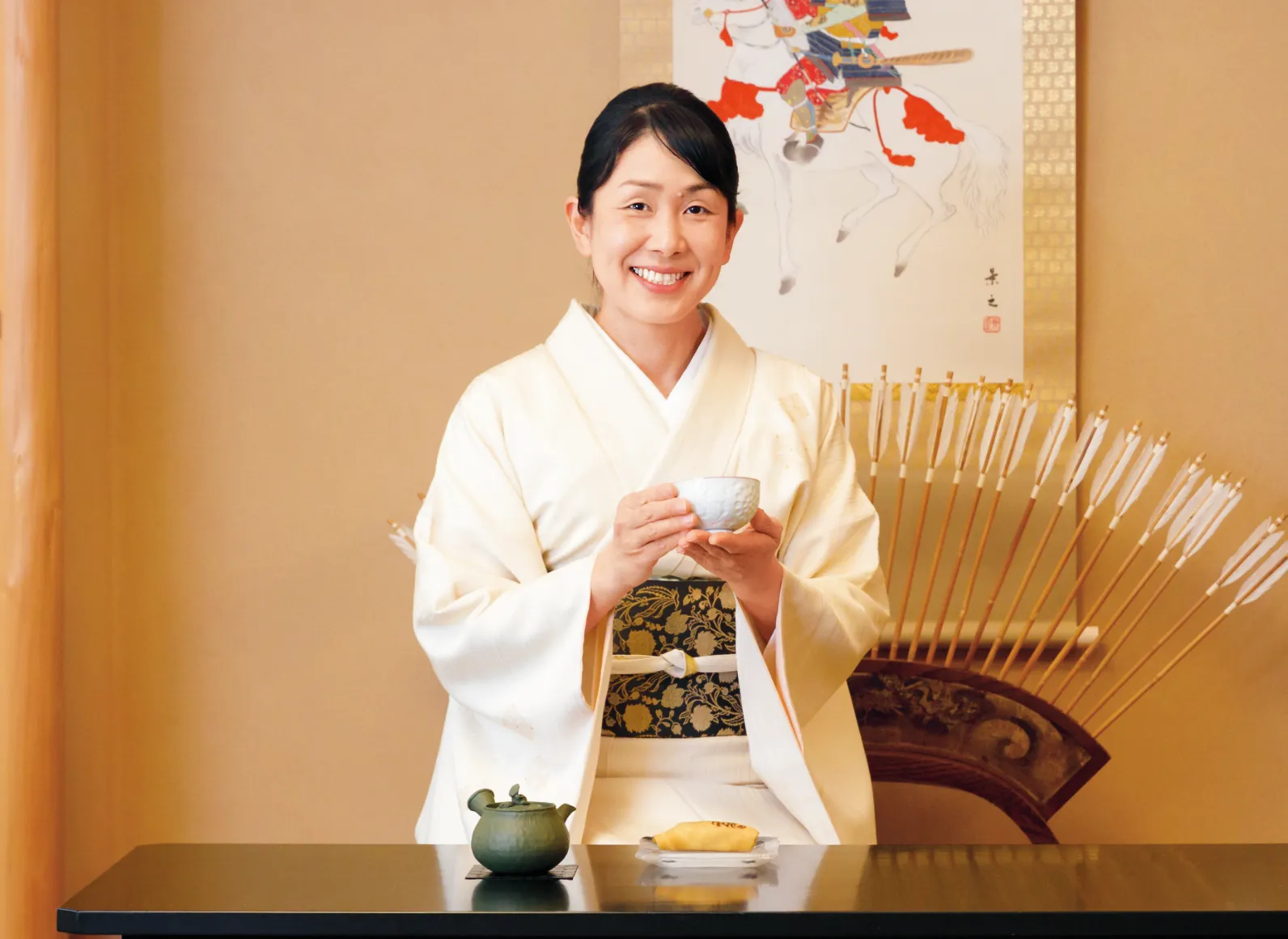 掛け軸の前で湯呑を持つ辻󠄀真奈美さんの画像