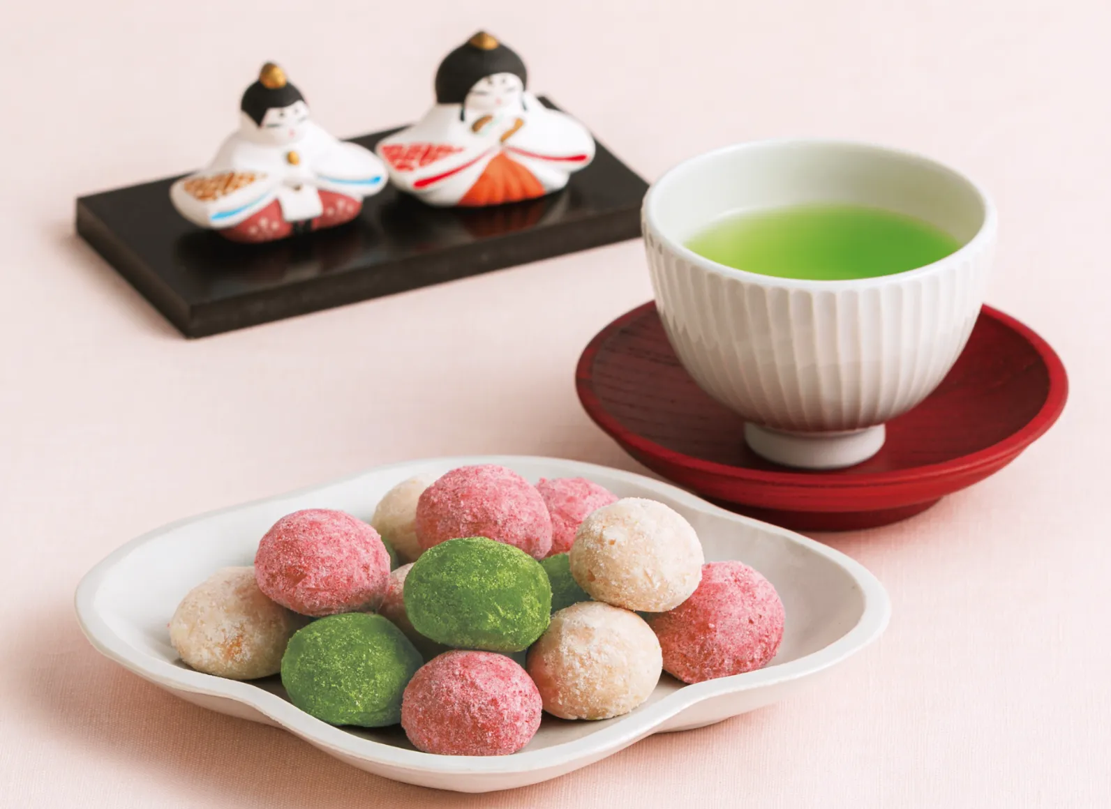 ポルボローネと湯呑みに入ったお茶、その奥にお内裏様とお雛様が置いてある画像