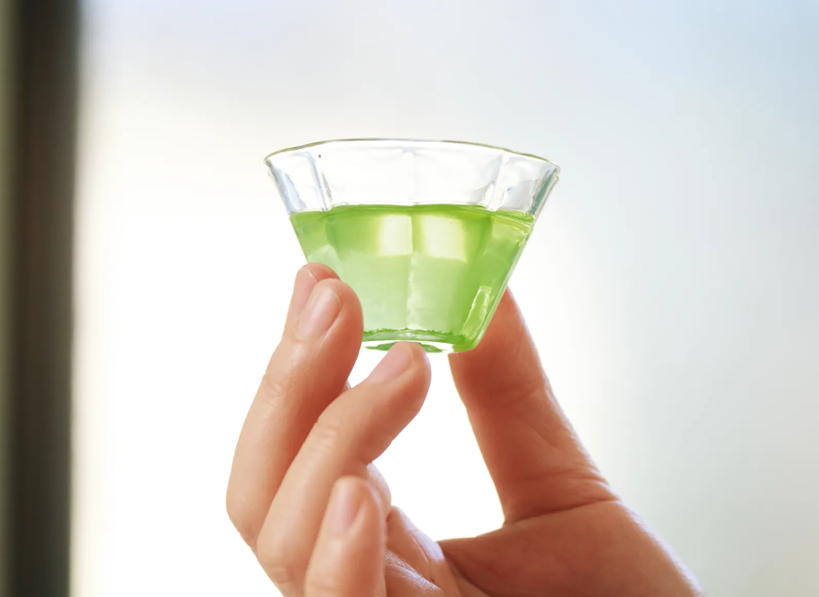 ガラスの器に注がれたお茶を光にかざす画像